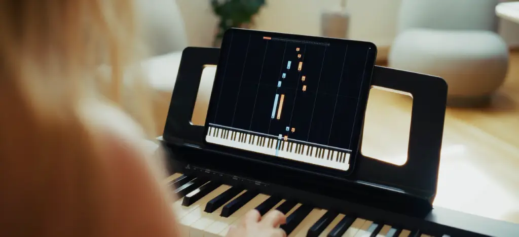 Woman learning to play piano with a piano learning app on a tablet.