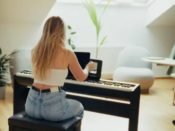 Woman placing an iPad running the Artie piano learning app on a digital piano stand