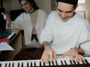 Two people playing and learning piano at home